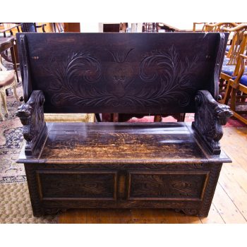 Carved oak monks bench with panel front. Back of the bench folds down to create a table or dumbwaiter and the seat lifts up for storage. Measures 122W x 50D x 102H cm. Price includes nationwide delivery.